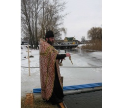 Священник освячує воду в річці Красній