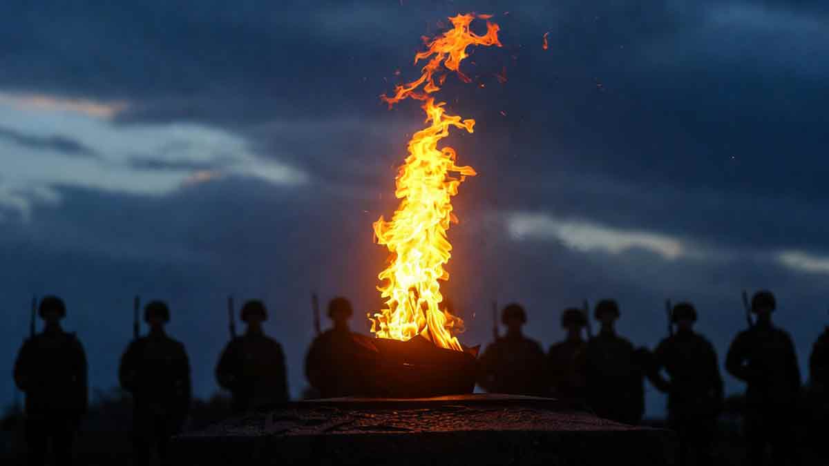 Вічний вогонь пам'яті, силуети українських воїнів у строю, вечірнє небо