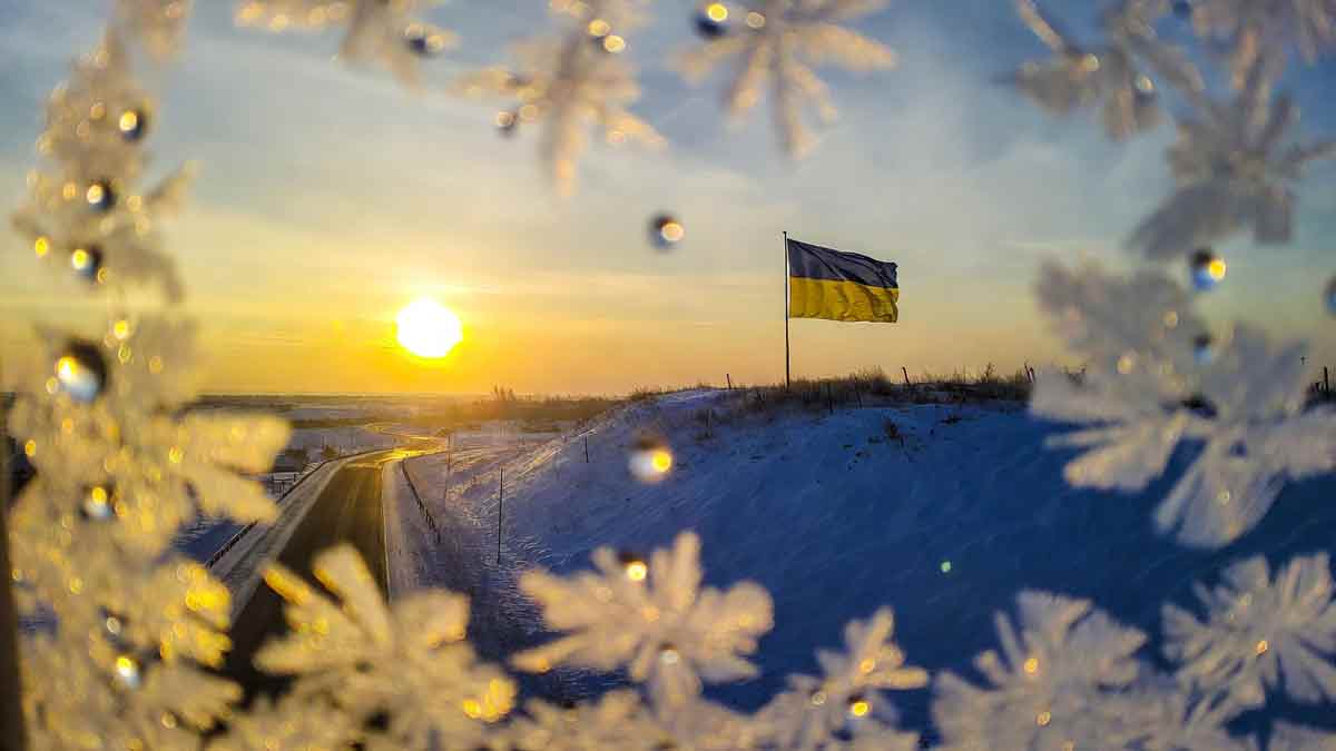 Український прапор на тлі зимового світанку, сліди на снігу ведуть вперед